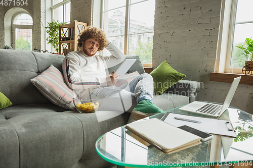 Image of Manager or student working from home while being insulated or keep quarantine \'cause of coronavirus COVID-19. Reading report, task, sitting on sofa.