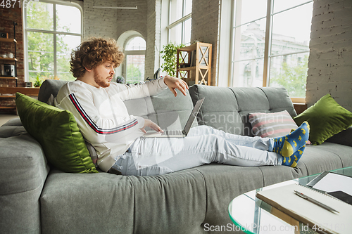 Image of Manager or student working from home while being insulated or keep quarantine \'cause of coronavirus COVID-19. Typing text, lying down on sofa.