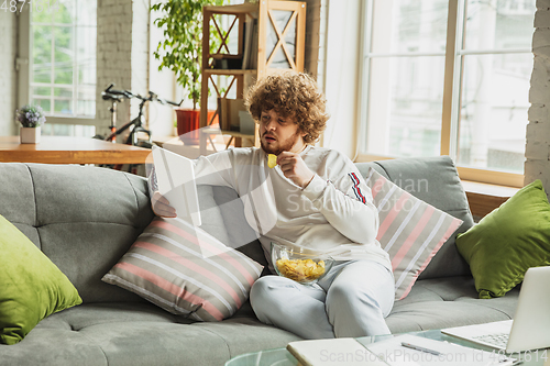 Image of Manager or student working from home while being insulated or keep quarantine \'cause of coronavirus COVID-19. Reading report, task, sitting on sofa.