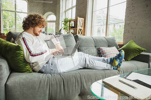 Image of Manager or student working from home while being insulated or keep quarantine \'cause of coronavirus COVID-19. Typing text, lying down on sofa.