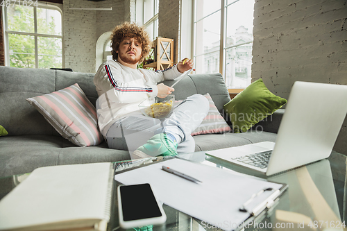 Image of Manager or student working from home while being insulated or keep quarantine \'cause of coronavirus COVID-19. Reading report, task, sitting on sofa.