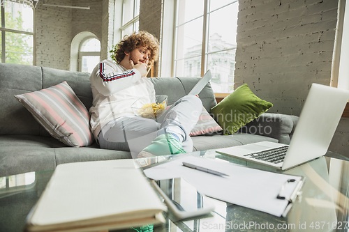 Image of Manager or student working from home while being insulated or keep quarantine \'cause of coronavirus COVID-19. Reading report, task, sitting on sofa.