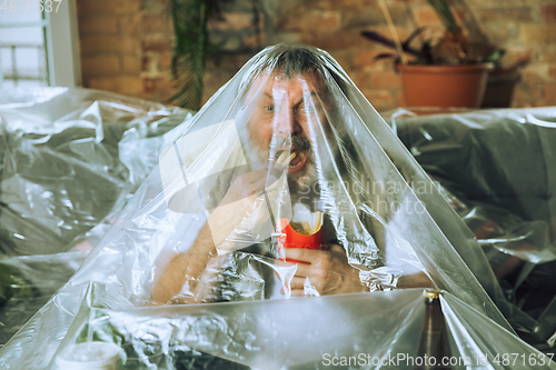 Image of Senior man covered with plastic, eating fast food and drinking beer - environmental pollution by people concept