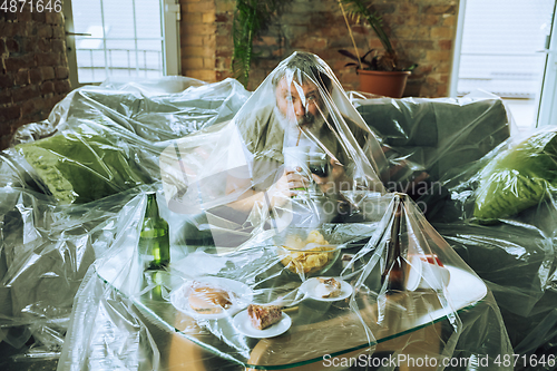Image of Senior man covered with plastic, eating fast food and drinking beer - environmental pollution by people concept