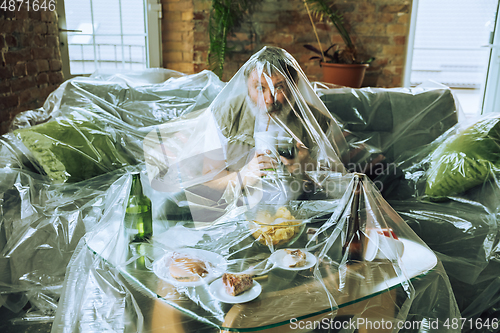 Image of Senior man covered with plastic, eating fast food and drinking beer - environmental pollution by people concept