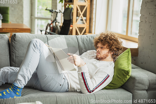 Image of Manager or student working from home while being insulated or keep quarantine \'cause of coronavirus COVID-19. Working lying down on sofa.