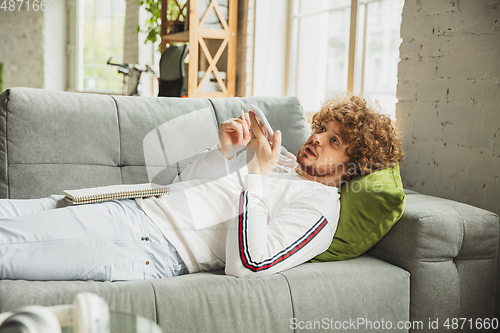 Image of Manager or student working from home while being insulated or keep quarantine \'cause of coronavirus COVID-19. Recording voice message lying down on sofa.