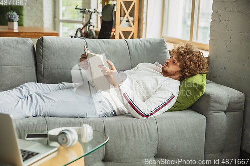 Image of Manager or student working from home while being insulated or keep quarantine \'cause of coronavirus COVID-19. Working lying down on sofa.