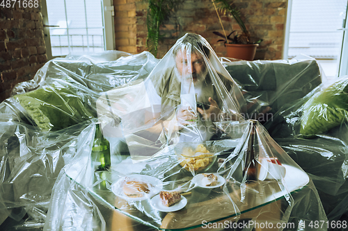 Image of Senior man covered with plastic, eating fast food and drinking beer - environmental pollution by people concept