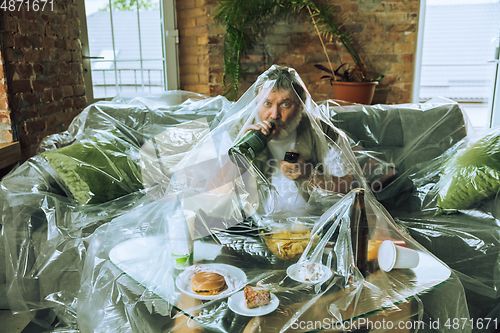 Image of Senior man covered with plastic, eating fast food and drinking beer - environmental pollution by people concept