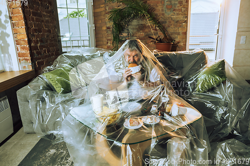 Image of Senior man covered with plastic, eating fast food and drinking beer - environmental pollution by people concept