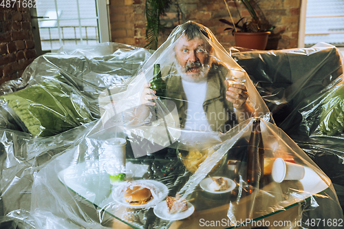 Image of Senior man covered with plastic, eating fast food and drinking beer - environmental pollution by people concept