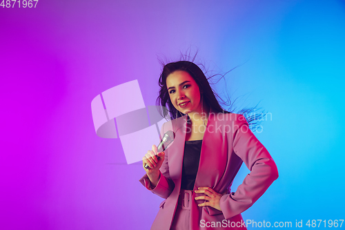 Image of Caucasian female singer portrait isolated on gradient studio background in neon light