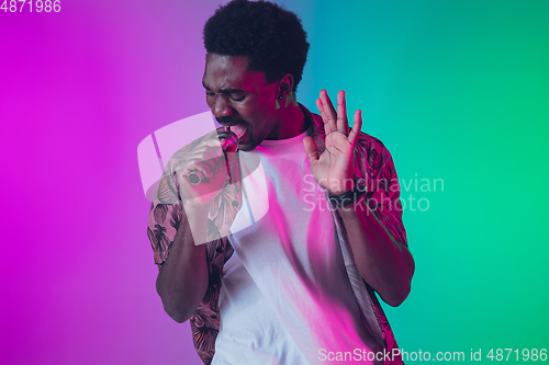 Image of African-american male singer portrait isolated on gradient studio background in neon light