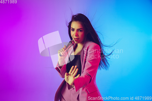 Image of Caucasian female singer portrait isolated on gradient studio background in neon light