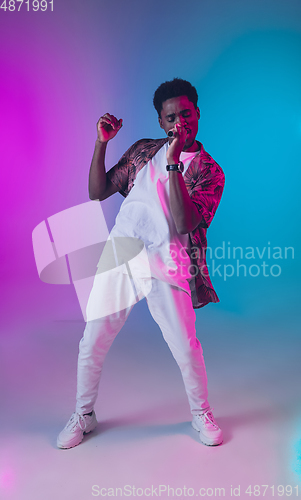 Image of African-american male singer portrait isolated on gradient studio background in neon light