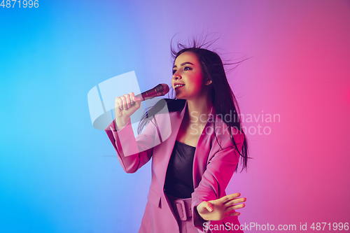 Image of Caucasian female singer portrait isolated on gradient studio background in neon light