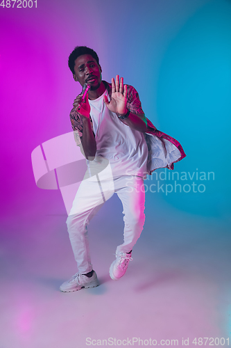 Image of African-american male singer portrait isolated on gradient studio background in neon light
