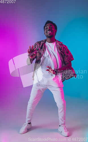 Image of African-american male singer portrait isolated on gradient studio background in neon light