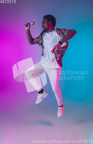 Image of African-american male singer portrait isolated on gradient studio background in neon light