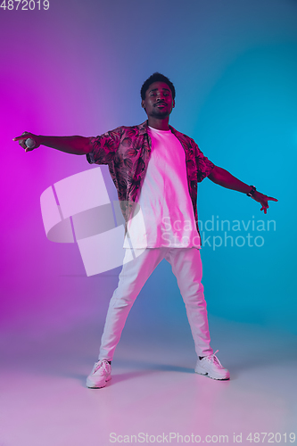 Image of African-american male singer portrait isolated on gradient studio background in neon light