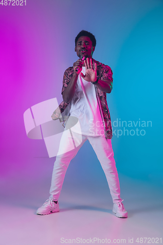 Image of African-american male singer portrait isolated on gradient studio background in neon light