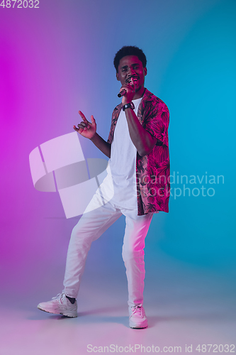 Image of African-american male singer portrait isolated on gradient studio background in neon light