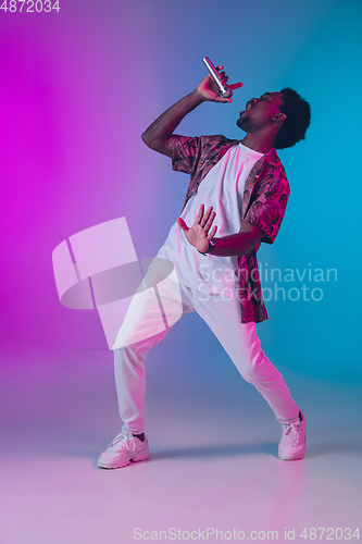 Image of African-american male singer portrait isolated on gradient studio background in neon light