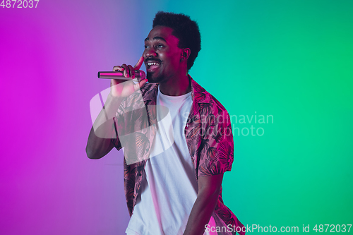 Image of African-american male singer portrait isolated on gradient studio background in neon light