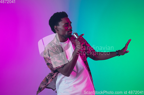 Image of African-american male singer portrait isolated on gradient studio background in neon light