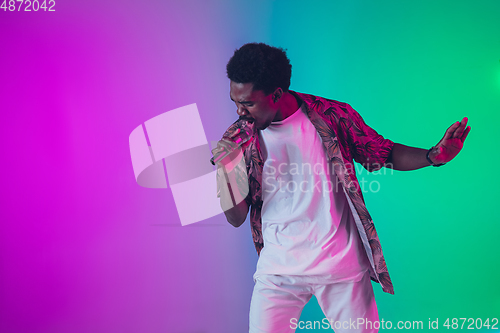Image of African-american male singer portrait isolated on gradient studio background in neon light