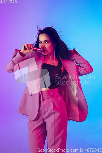 Image of Caucasian female singer portrait isolated on gradient studio background in neon light