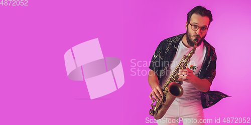 Image of Young caucasian jazz musician playing the saxophone in neon light, flyer with copyspace for ad