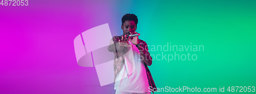 Image of African-american male singer portrait isolated on gradient studio background in neon light, flyer with copyspace