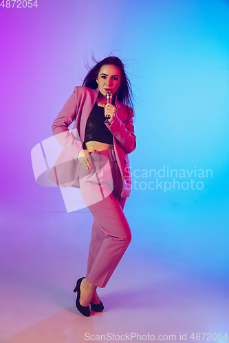 Image of Caucasian female singer portrait isolated on gradient studio background in neon light