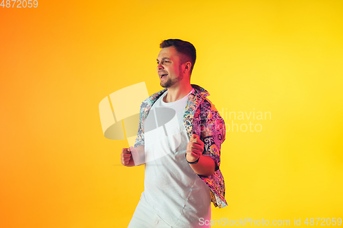 Image of Young caucasian musician, dancer, party host, DJ on gradient background in neon light