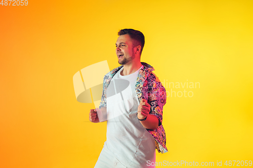 Image of Young caucasian musician, dancer, party host, DJ on gradient background in neon light