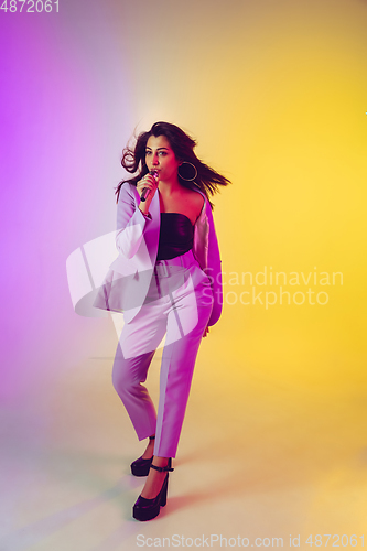 Image of Caucasian female singer portrait isolated on gradient studio background in neon light