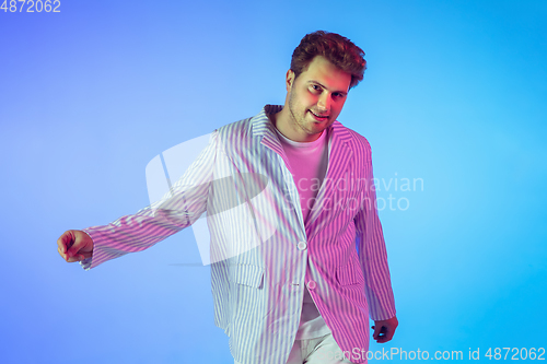 Image of Young caucasian musician, dancer, party host, DJ on gradient background in neon light