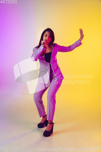 Image of Caucasian female singer portrait isolated on gradient studio background in neon light