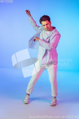 Image of Young caucasian musician, dancer, party host, DJ on gradient background in neon light