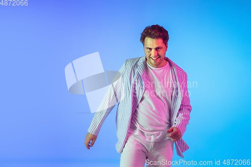 Image of Young caucasian musician, dancer, party host, DJ on gradient background in neon light