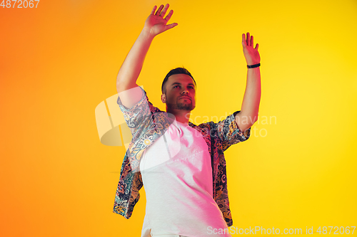 Image of Young caucasian musician, dancer, party host, DJ on gradient background in neon light