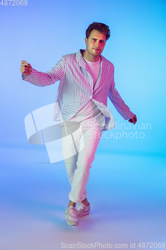 Image of Young caucasian musician, dancer, party host, DJ on gradient background in neon light