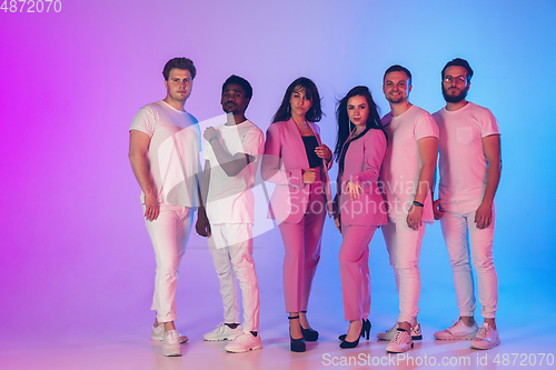 Image of Group of young multiethnic musicians created band, posing in neon light on gradient background