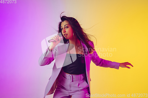 Image of Caucasian female singer portrait isolated on gradient studio background in neon light