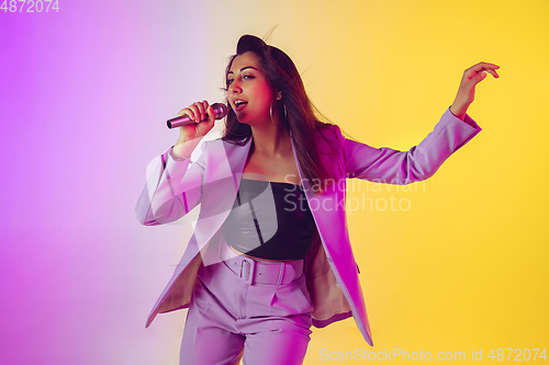 Image of Caucasian female singer portrait isolated on gradient studio background in neon light