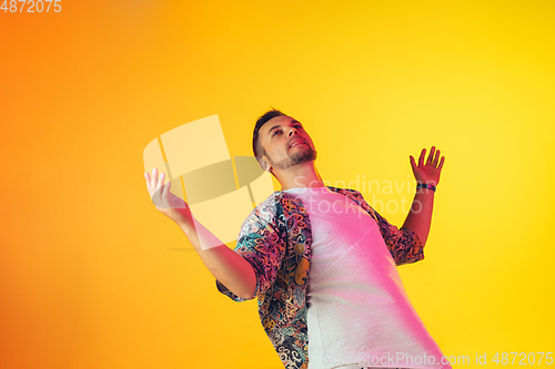 Image of Young caucasian musician, dancer, party host, DJ on gradient background in neon light