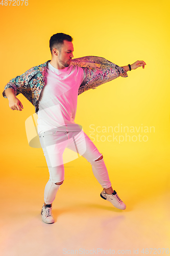 Image of Young caucasian musician, dancer, party host, DJ on gradient background in neon light