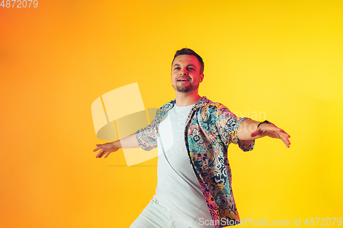 Image of Young caucasian musician, dancer, party host, DJ on gradient background in neon light